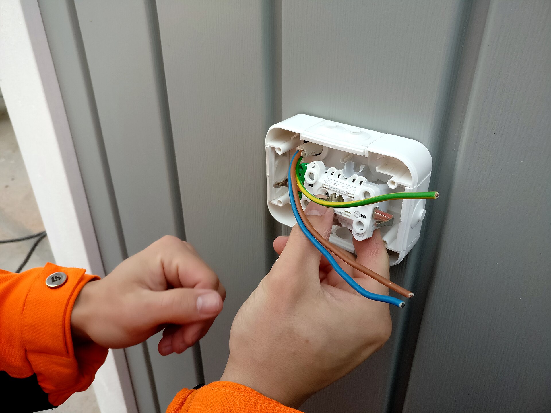 Hands wiring a wall socket back box